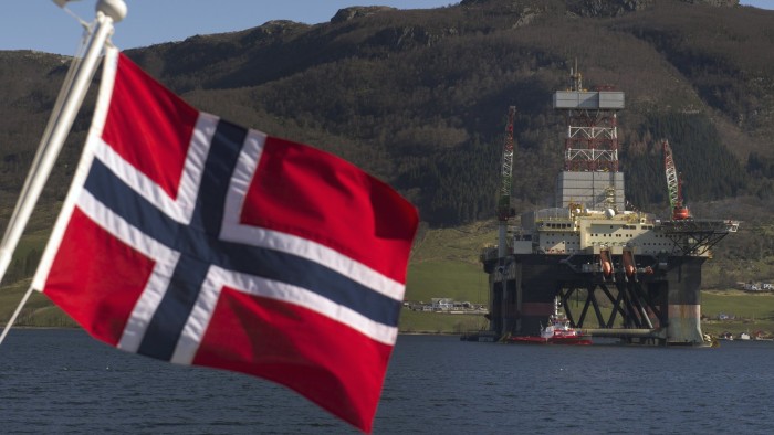 The New Scarabeo 8 Ultra Deepwater Oil Rig...A Norwegian national flag flies from a vessel near the Scarabeo 8 deepwater oil drilling rig, operated by ENI Norge AS, in Olensvag, Norway, on Tuesday, April 3, 2012. The world's seventh-largest oil exporter boasts no net debt, adding to its appeal as an alternative to the debt-riddled euro area. Photographer: Kristian Helgesen/Bloomberg