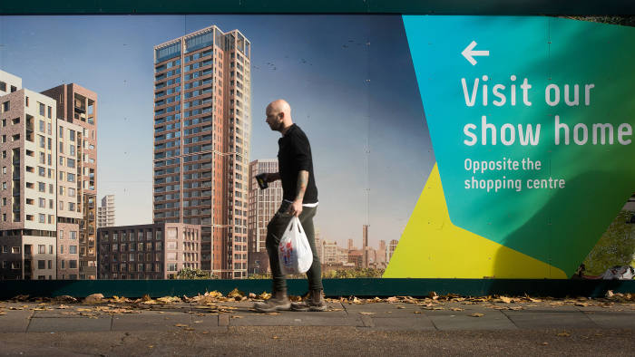 A pedestrian walks past a hoarding advertising a block of flats, currently under construction, in London, U.K., on Monday, Oct. 31, 2016.