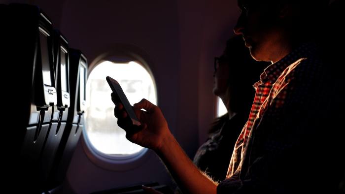 A passenger looks at his Apple iPhone on a commercial flight from Sydney, Australia, to Auckland, New Zealand, July 8, 2017. REUTERS/Jason Reed - RC14238A9010