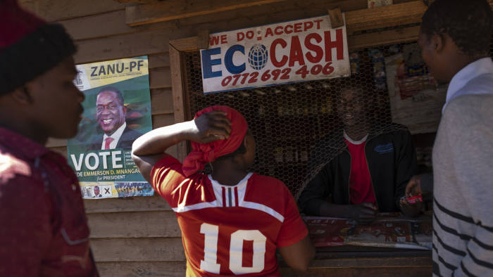 HARARE, ZIMBABWE - JULY 27: Vendors use a street shack that accepts EcoCash' to buy goods in the Mbare neighborhood on July 27, 2018 in Harare, Zimbabwe. EcoCash is an electronic payment system that can be used via a mobile phone and is popular as many Zimbabweans have limited accessibility to cash. Zimbabweans go to the polls on July 30th to vote for a new president in the first election since Robert Mugabe, who led the country for 37 years after it gained independence in 1980, was ousted from power last year. (Photo by Dan Kitwood/Getty Images)