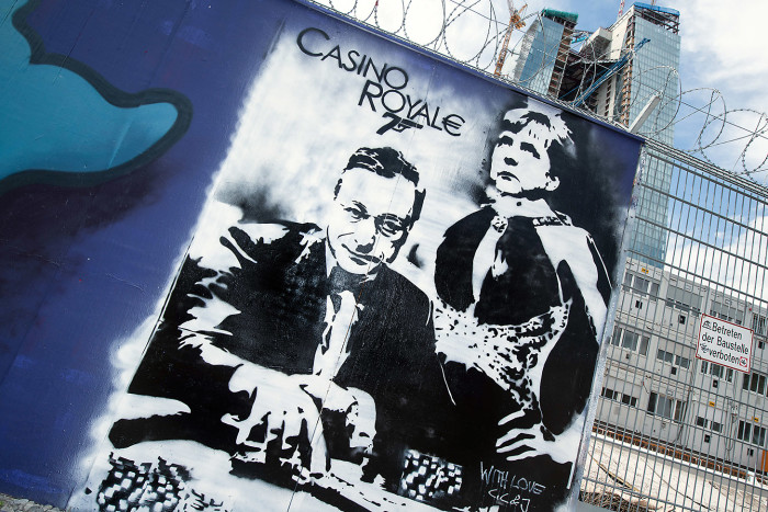 D7MNWK Graffiti with ECB President Mario Draghi and German Chancellor Angela Merkel is painted onto a fence at the construction site of the new European Central Bank (ECB) in Frankfurt Main, Germany, 10 May 2013. The painting and title are reminiscent of a James Bond Movie. Photo: BORIS ROESSLER