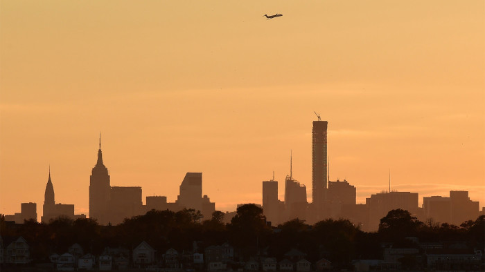 An airplane flies over the midtown Manhattan skyline on a brisk autumn afternoon October 30, 2014 in New York