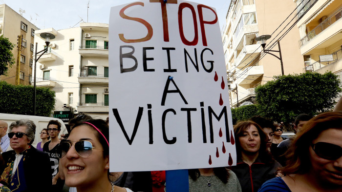 Women, one holding a placard, take part in a rally, notably to denounce domestic violence, on the &quot;International Women's Day&quot; on March 8, 2014 in front of the National Museum in the capital Beirut