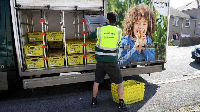 WEYMOUTH, ENGLAND - MARCH 27: Morrisons supermarket delivery van delivers to a house on March 27, 2020 in Weymouth, United Kingdom. The UK's supermarkets have been struggling to keep up with the high demand of online delivery orders. Stores are unable to offer same-day delivery while some are prioritising vulnerable and elderly people for online deliveries. The Coronavirus (COVID-19) pandemic has spread to many countries across the world, claiming over 20,000 lives and infecting hundreds of thousands more. (Photo by Finnbarr Webster/Getty Images)