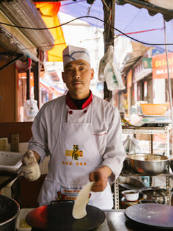 Mr. Dong prepares the thin pancakes to be used for spring rolls, Qingyang Market.