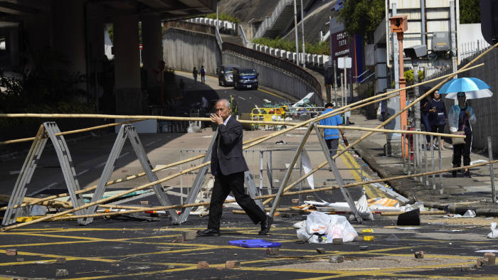A man crosses in front of a roadblock set up by pro-democracy protesters outside the Hong Kong Baptist University, in Hong Kong, Wednesday, Nov. 13, 2019. Police have increased security around Hong Kong and its university campuses as they brace for more violence after sharp clashes overnight with anti-government protesters. (AP Photo/Vincent Yu)