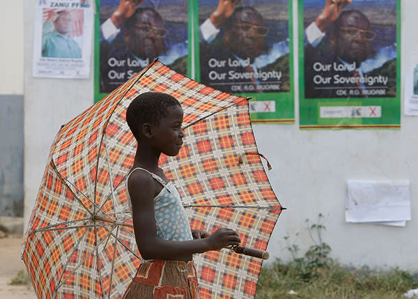 A child walks past election posters in Harare, Zimbabwe, in 2008