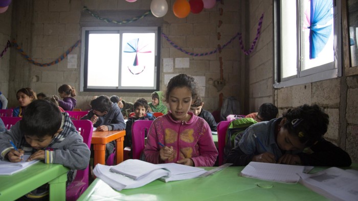Syrian refugee children write inside their books during an Arabic class inside a classroom in Akkar, north of Lebanon, Thursday, December 18, 2014.