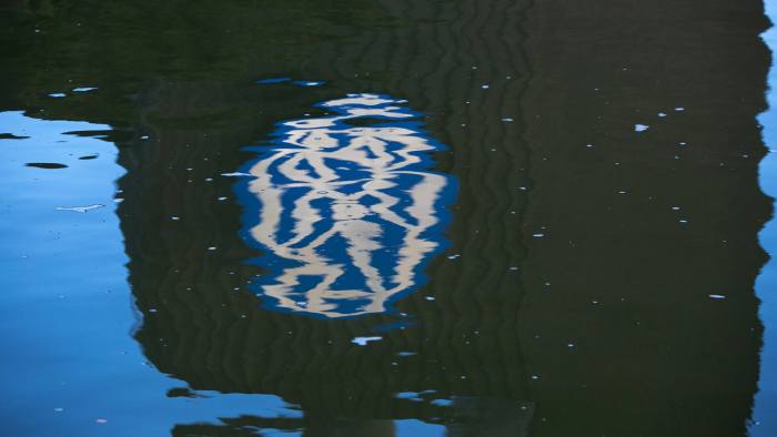 The VW logo is reflected in the Aller river outside the Volkswagen AG headquarters in Wolfsburg, Germany, on Wednesday, Sept. 23, 2015. Volkswagen's escalating scandal over emissions-test cheating is beginning to ripple across the $10 trillion global corporate bond market. Photographer: Krisztian Bocsi/Bloomberg