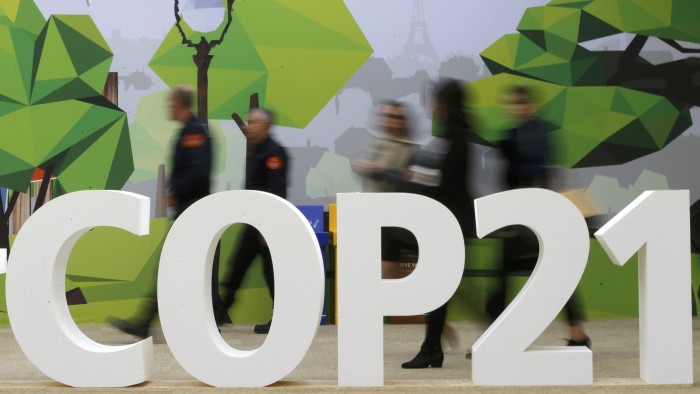 People walk walks past the COP21 logo in the Climate Generations area during the World Climate Change Conference 2015 (COP21) at Le Bourget, near Paris, France, December 1, 2015. REUTERS/Stephane Mahe