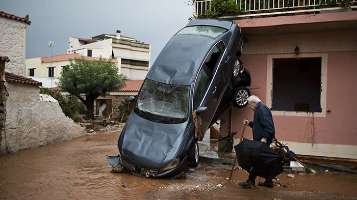 A man walks past a car moved by the force of flood water and a damaged house in the town of Mandra western Athens, on Thursday, Nov. 16, 2017. Greece's fire department says rescue crews are searching for six people reported missing in the western Athens area following major flash flooding that left at least 14 people dead.(AP Photo/Petros Giannakouris)