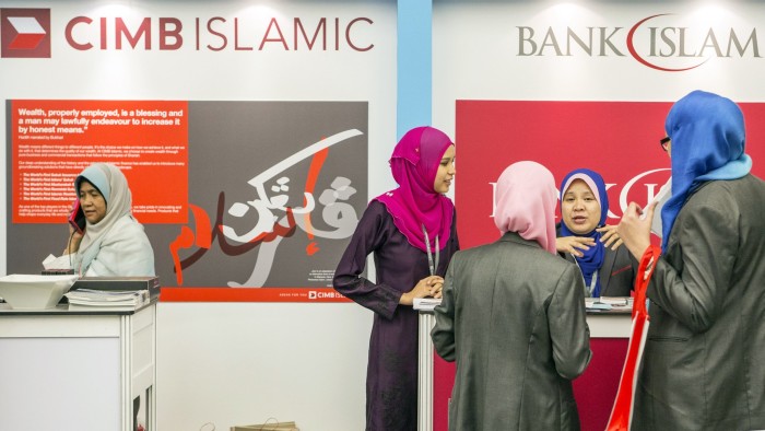 Women stand at the CIMB Islamic Banking Bhd. and the Bank Islam Malaysia Bhd. booths at the Global Islamic Finance Forum in Kuala Lumpur, Malaysia, on Wednesday, Sept. 3, 2014. The forum runs through Sept. 4. Photographer: Charles Pertwee/Bloomberg