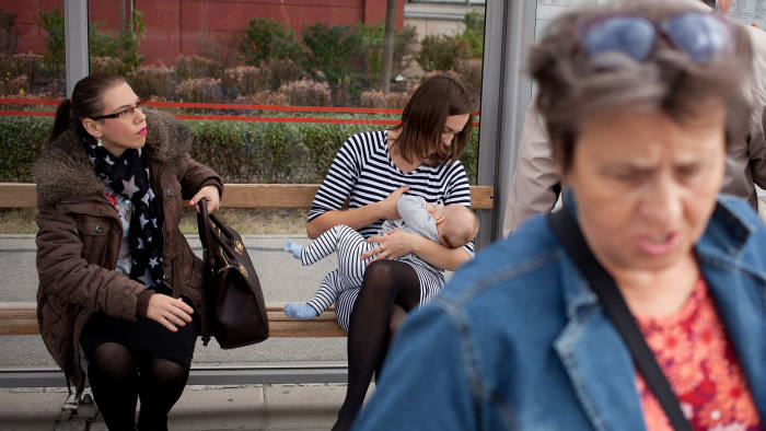 While you wait: Marta Andreasik breastfeeds her six-month-old daughter Amelia at a bus stop in Warsaw