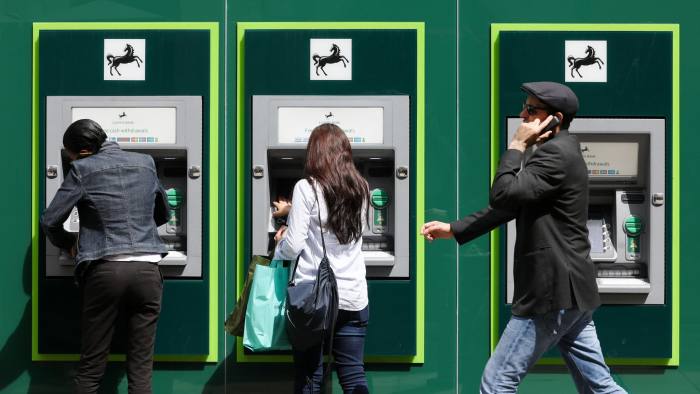 People use automated teller machines (ATMs) outside a Lloyds bank branch, a unit of Lloyds Banking Group Plc, in London, U.K., on Wednesday, May 31, 2017. Lloyds is in talks to lease a new London office with room for about 1,000 workers in an effort to consolidate its locations in the capital and help save 100 million pounds ($130 million), two people familiar with the plan said. Photographer: Luke MacGregor/Bloomberg