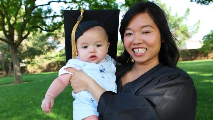 A mother graduates holding her baby daughter