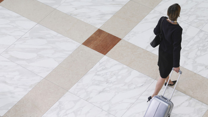 Businesswoman walking with suitcase on tiled floor