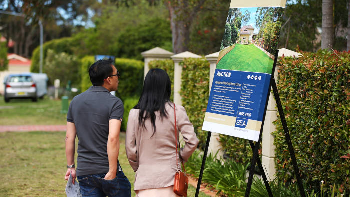 People look at a Smyth Estate Agents auction sign on display outside a house in the suburb of Beacon Hill in Sydney, Australia, on Saturday, Oct. 18, 2014. Sydney���s median home price rose 14 percent from a year earlier in September to A$655,000 ($568,900), an RP Data CoreLogic Home Value Index showed Oct. 1. Photographer: Brendon Thorne/Bloomberg