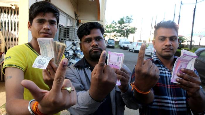 epa05633552 Indian men show their inked fingers as they hold new Indian currency notes at a bank in Bhopal, India, 16 November 2016. Indian Bank officials started leaving an ink mark on fingers of people who have exchanged their discontinued Rupee notes for new ones to prevent people from visiting the branch repeatedly. Indian Prime Minister Narendra Modi announced the elimination of the 500 and 1,000 rupee bills (7.37 and 14.73 US dollars, respectively), hours before the measure took effect at midnight 08 November, for the purpose of fighting against 'black money' (hidden assets) and corruption in the country. The decision sparked some protests, while storekeepers complained about dwindling sales because many citizens lack the cash to buy the most basic products, as lines get longer at ATMs and banks. EPA/SANJEEV GUPTA
