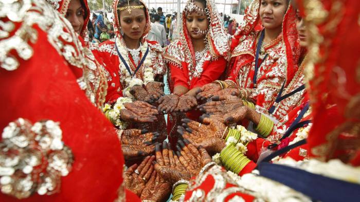 Muslim brides show their hands decorated with henna paste during a mass wedding ceremony in Ahmedabad