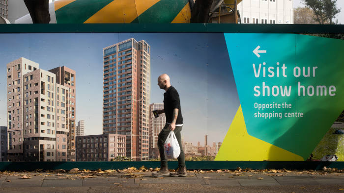 A pedestrian walks past a hoarding advertising a block of flats, currently under construction, in London, U.K., on Monday, Oct. 31, 2016. London property prices are set to fall next year as uncertainty about Britain's exit from the European Union damps the U.K. housing market, according to the Centre for Economics and Business Research. Photographer: Simon Dawson/Bloomberg