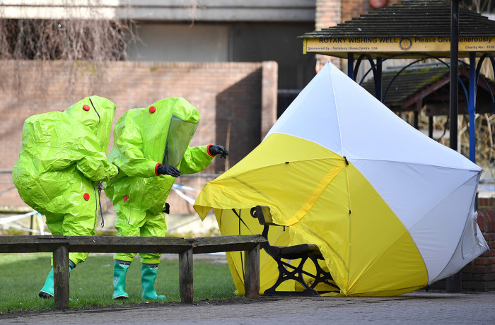 Members of the emergency services in green biohazard suits afix the tent over the bench where a man and a woman were found on March 4 in critical condition at The Maltings shopping centre in Salisbury, southern England, on March 8, 2018 after the tent became detached. British detectives on March 8 scrambled to find the source of the nerve agent used in the "brazen and reckless" attempted murder of a Russian former double-agent and his daughter. Sergei Skripal, 66, who moved to Britain in a 2010 spy swap, is unconscious in a critical but stable condition in hospital along with his daughter Yulia after they collapsed on a bench outside a shopping centre on Sunday. / AFP PHOTO / Ben STANSALLBEN STANSALL/AFP/Getty Images