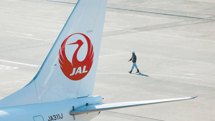 An airport staff member walks next to a Japan Airlines aircraft at Haneda Airport in Tokyo February 4, 2013