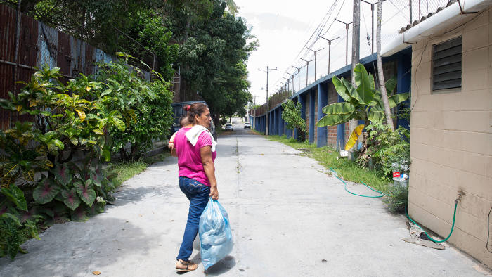 Maribel carries her grandson as she goes to visit her daughter in a juvenile detention centre in San Salvador