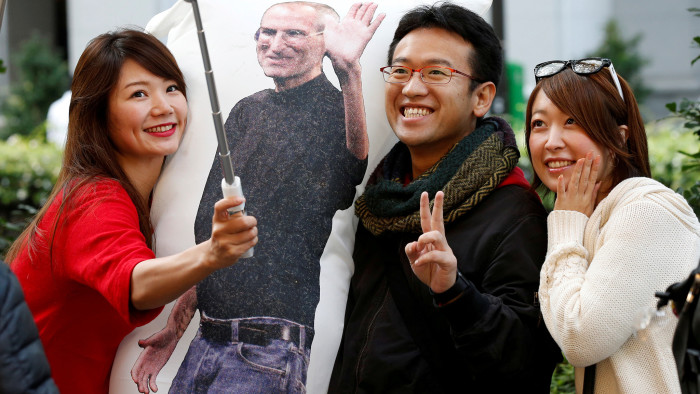Ayano Tominaga (L) and other customers pose for a selfie photo with a cushion printed with a portrait of Apple co-founder Steve Jobs on it, as they wait in queue for the release of Apple's new iPhone X in front of the Apple Store in Tokyo's Omotesando shopping district, Japan, November 3, 2017.  REUTERS/Toru Hanai     TPX IMAGES OF THE DAY