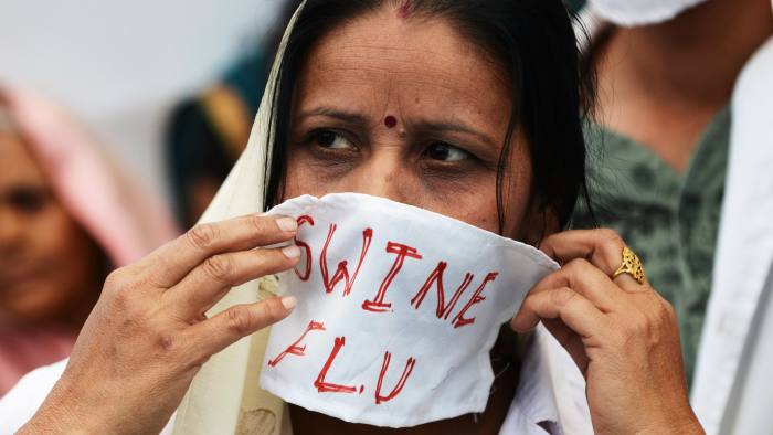 An Indian activist adjusts her face masks as other activists dressed as medical staff and patients perform a street play on the ongoing H1N1 swine flu outbreak in Ahmedabad on March 15, 2013. The activists claim that the Gujarat state government has failed to contain the outbreak, with some 110 deaths in the past three months. AFP PHOTO / Sam PANTHAKY (Photo credit should read SAM PANTHAKY/AFP/Getty Images)