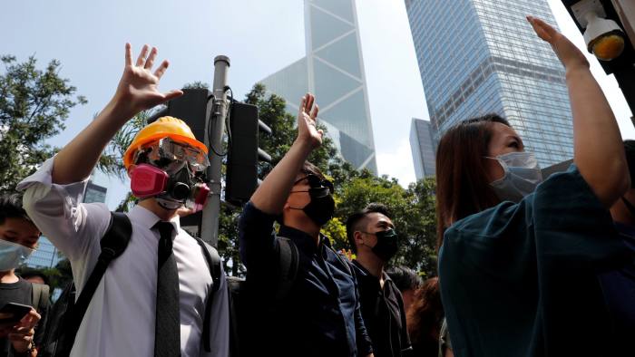 FILE PHOTO: Anti-government office workers wearing masks attend a lunch time protest, after local media reported on an expected ban on face masks under emergency law, at Central, in Hong Kong, China, October 4, 2019. Cheung Kong Center can be seen at right in the background. REUTERS/Tyrone Siu/File Photo To match Special Report HONGKONG-PROTESTS/TYCOONS