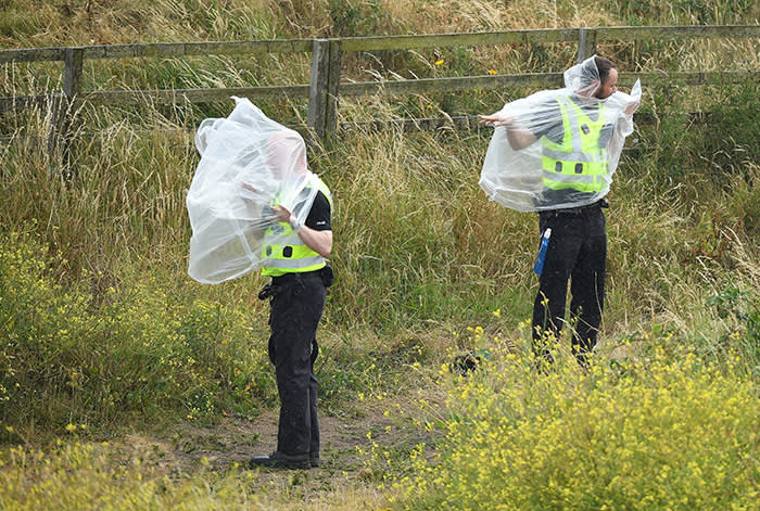 TURNBERRY, SCOTLAND - JULY 15: Police officers attempt to don ponchos as U.S. President Donald Trump plays a round of golf at Trump Turnberry Luxury Collection Resortduring the U.S. President's first official visit to the United Kingdom on July 15, 2018 in Turnberry, Scotland. The President of the United States and First Lady, Melania Trump on their first official visit to the UK after yesterday's meetings with the Prime Minister and the Queen is in Scotland for private weekend stay at his Turnberry. (Photo by Leon Neal/Getty Images)