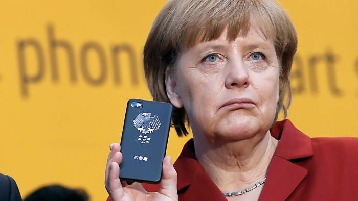 File photo of German Chancellor Merkel holding a smartphone featuring high security Secusite software in Hanover...German Chancellor Angela Merkel (R) reacts as she holds a BlackBerry Z10 smartphone featuring high security Secusite software, used for governmental communication, at the booth of Secusmart during her opening tour with Poland's Prime Minister Donald Tusk on the CeBit computer fair in Hanover in this March 5, 2013 file photo. Germany's Foreign Minister has summoned the United States' ambassador to Germany, John B. Emerson, to discuss information obtained by Berlin that the U.S. may have monitored Merkel's mobile phone, a government spokesman said on October 24, 2013. REUTERS/Fabrizio Bensch/Files (GERMANY - Tags: BUSINESS SCIENCE TECHNOLOGY POLITICS)