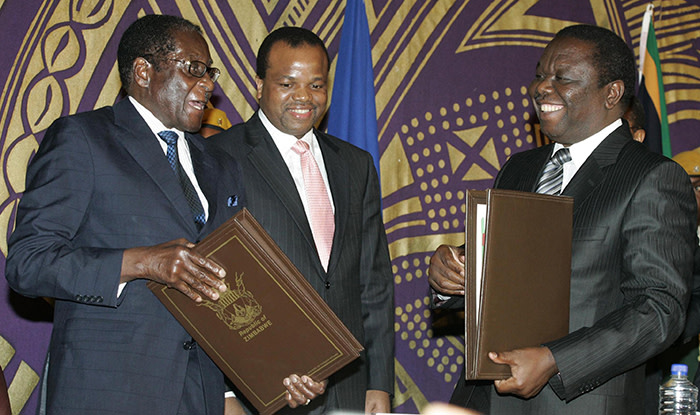 Zimbabwe's President Robert Mugabe (L) exchanges documents with opposition leader Morgan Tsvangirai (R) after signing a power-sharing deal at Rainbow Towers hotel in Harare September 15, 2008. Mugabe signed a power-sharing agreement with opposition rival Tsvangirai on Monday, relinquishing some of his powers for the first time in nearly three decades of iron rule. Looking on is King Mswati of Swaziland (C). REUTERS/Philimon Bulawayo (ZIMBABWE) - GM1E49F1ORF01
