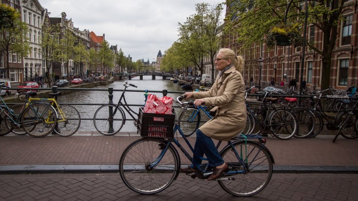 View of a canal in Amsterdam with a woman on a bicycle on April 12, 2017. / AFP PHOTO / Aurore Belot (Photo credit should read AURORE BELOT/AFP/Getty Images)