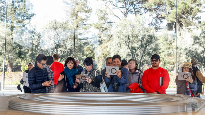 People try out the augmented reality system that shows what the finished Apple Park will look like at the opening of the Apple Park Visitor Center on November 17, 2017 in Cupertino, California. / AFP PHOTO / Amy Osborne (Photo credit should read AMY OSBORNE/AFP/Getty Images)