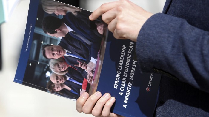 Conservative Party supporters hold copies of their party's manifesto after David Cameron, U.K. prime minister and leader of the Conservative Party, launched the party's 2015 general election manifesto in Swindon, U.K., on Tuesday, April 14, 2015. Cameron is pinning his Conservative Party's hopes of re-election by offering 1.3 million poorer families the chance to buy their own homes. Photographer: Chris Ratcliffe/Bloomberg