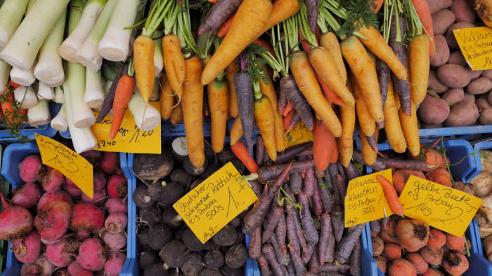 A large variety of carrots in many colours and other winter vegetables with pricetags and names at a market stall in Mainz, December 2019