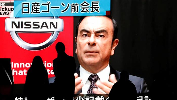 Passersby are silhouetted as a huge street monitor broadcasts news reporting ousted Nissan Motor chairman Carlos Ghosn's indictment and re-arrest in Tokyo, Japan December 10, 2018. REUTERS/Issei Kato - RC18968DB690