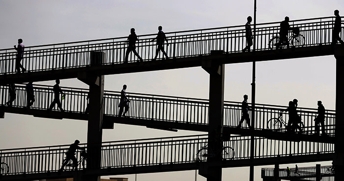 TOPSHOT - Asian workers working in Dubai are seen waling at a footbridge on February 14, 2018. / AFP PHOTO / KARIM SAHIBKARIM SAHIB/AFP/Getty Images