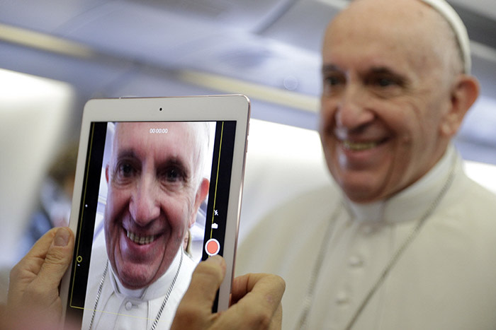 Pope Francis is recorded with a tablet as he greets journalists on board the flight to Bogota, Colombia, Wednesday, Sept. 6, 2017. Pope Francis is traveling to Colombia on a five-day apostolic trip during which he will visit the cities of Bogota, Villavicencio, Medellin and Cartagena. (AP Photo/Andrew Medichini)
