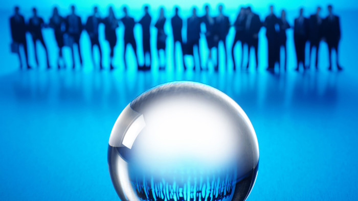 A group of men and women standing behind a crystal ball