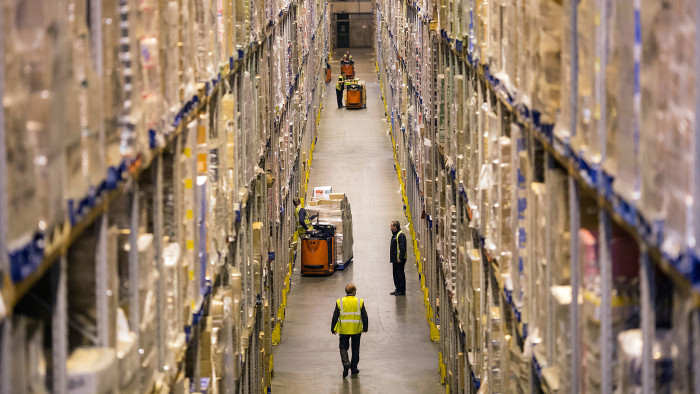 Employees drive pallet trucks as they move goods from storage racks ahead of shipping inside Poundland's goods distribution warehouse, operated by Poundland Holdings Ltd., in Bilston, U.K., on Friday, Dec. 20, 2013. Photographer: Simon Dawson/Bloomberg