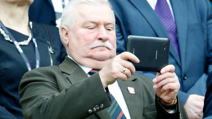 Former Polish President Lech Walesa (C) looks at his tablet computer before kick off of the semi final match of the UEFA EURO 2012 between Germany and Italy in Warsaw, Poland