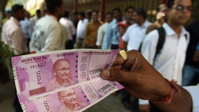 An Indian man displays new 2000 rupee notes outside the Reserve Bank of India (RBI) in Mumbai on November 10, 2016. Long queues formed outside banks in India as they reopened for the first time since the government's shock decision to withdraw the two largest denomination notes from circulation. / AFP PHOTO / PUNIT PARANJPEPUNIT PARANJPE/AFP/Getty Images