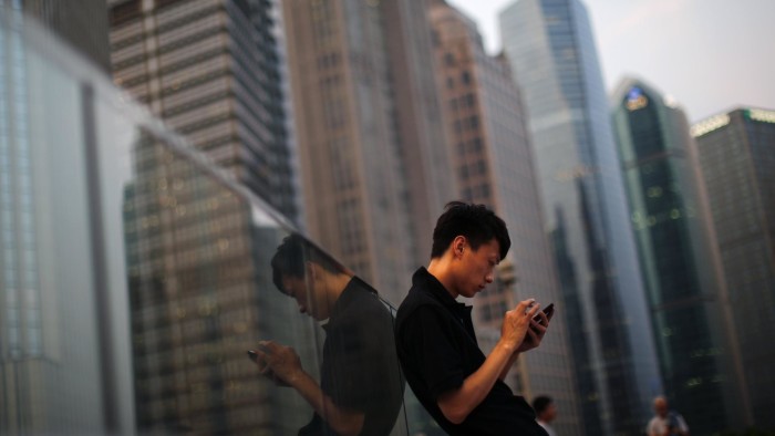 A man looks at the screen of his mobile phone at Pudong financial district in Shanghai