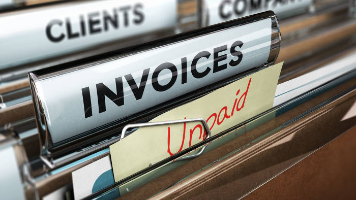 Close up on a file tab with the word invoice and a note where it is handwritten unpaid with blur effect.