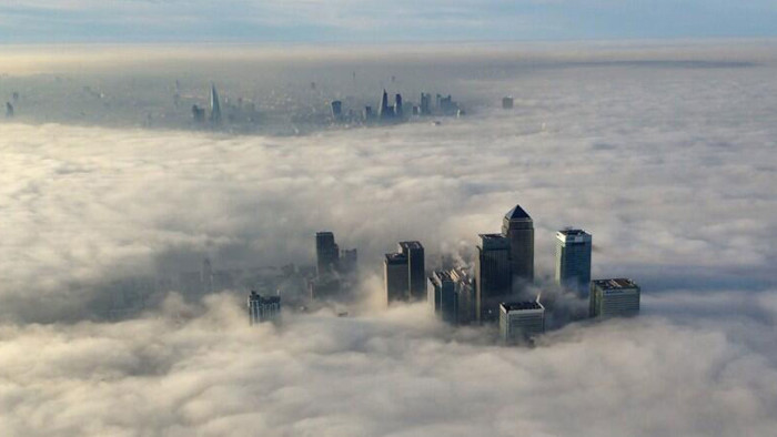The Canary Wharf financial district and central London emerge from morning fog