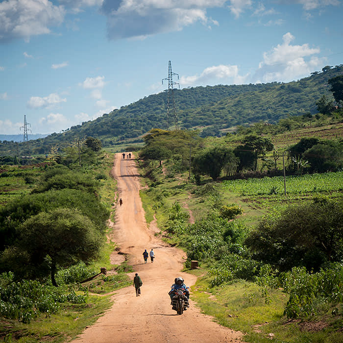 Motorbike drives along dirt road track past walking pedestrians on their way to Mbulu, Manyara district, Tanzania, East Africa. (photo by Andrew Aitchison / In pictures via Getty Images)