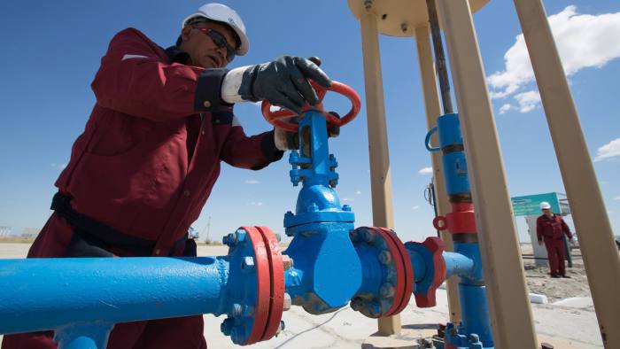 An oil worker adjusts the wheel of a flow valve on a modern oil pumping unit at an oilfield operated by Embamunaigas, a unit of KazMunaiGas Exploration Production, in Akkystau village, near Atyrau, Kazakhstan, on Saturday, July 4, 2015. The majority Muslim country is central Asia's biggest oil producer. Photographer: Andrey Rudakov/Bloomberg