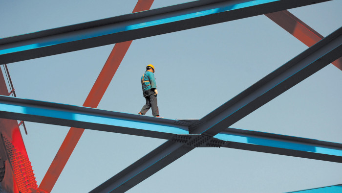 A man walks along a steel beam